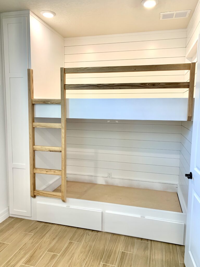 Custom white wood bunk beds with natural wood ladder and railing